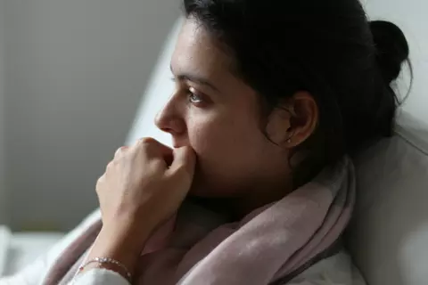 Vrouw met hand voor de mond, kijkt angstig