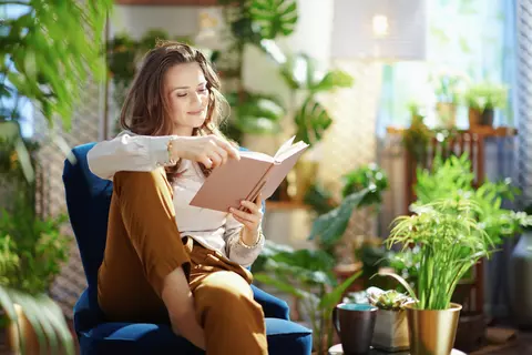 Vrouw leest boek in kamer met planten